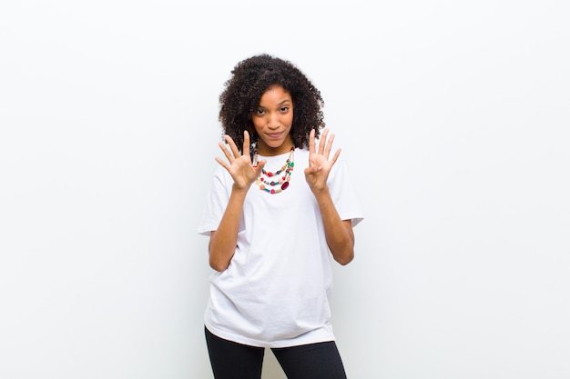 Молодая спокойная афроамериканская женщина, улыбающаяся и выглядящая дружелюбной, показывающая номер девять или девятый рукой вперед, считая вниз