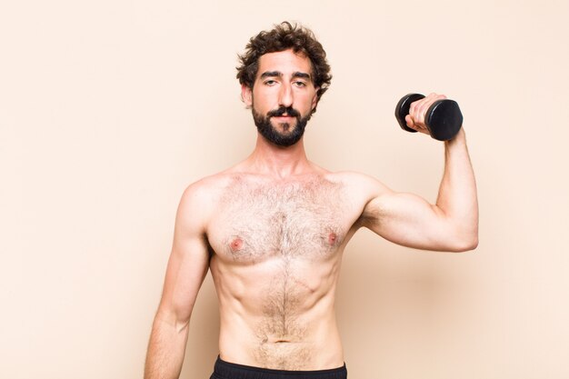 Photo young cool bearded man lifting a dumbbell fitness concept