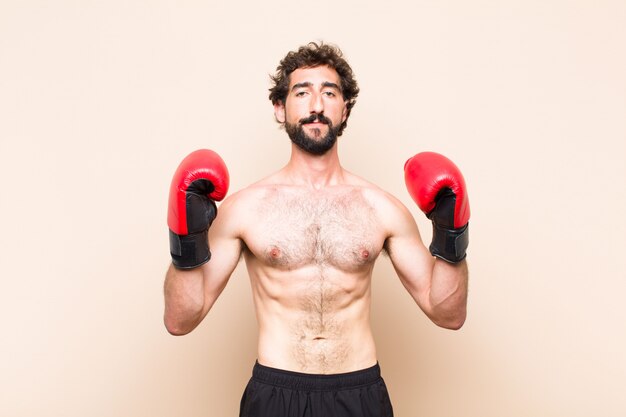 Young cool bearded man with boxing gloves and fighting fitness concept