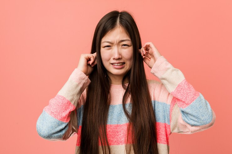 Photo 若いクールな中国人女性が彼の手で耳を覆っています。