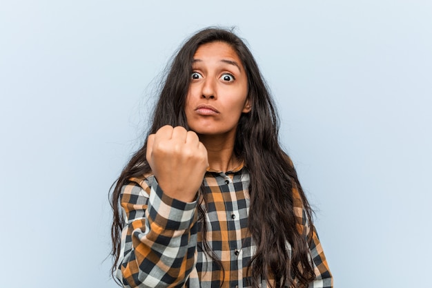 Young cool indian woman showing fist to camera, aggressive facial expression.