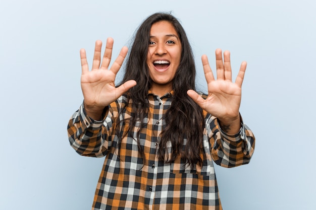 Молодая спокойная индийская женщина показывая номер десять с руками.