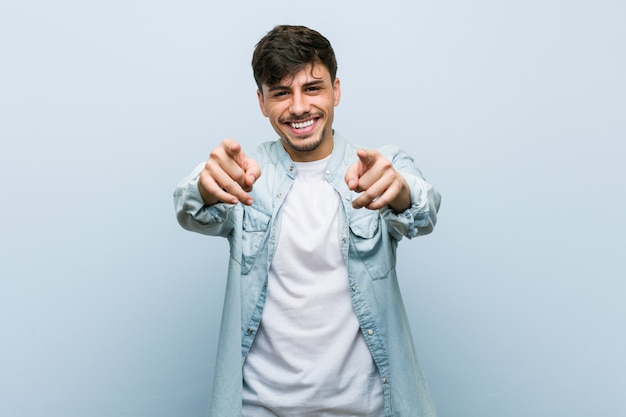 Young cool man cheerful smiles pointing to front