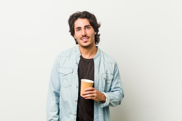 Young cool man drinking a coffee happy, smiling and cheerful.