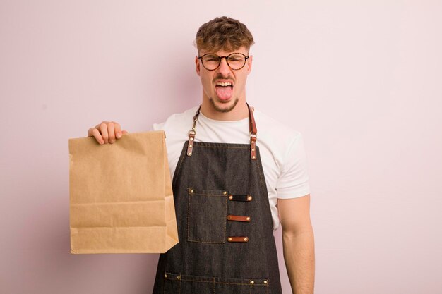 Young cool man feeling disgusted and irritated and tongue out deliveryman and fast food