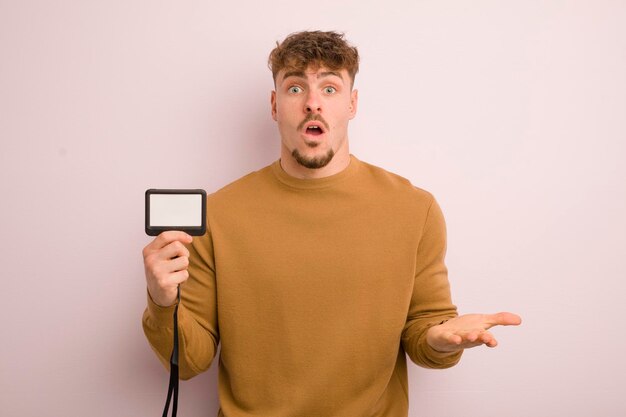 Young cool man feeling extremely shocked and surprised vip pass id concept