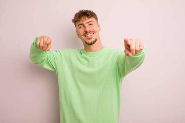 Young cool man feeling happy and confident pointing to camera with both hands and laughing choosing you