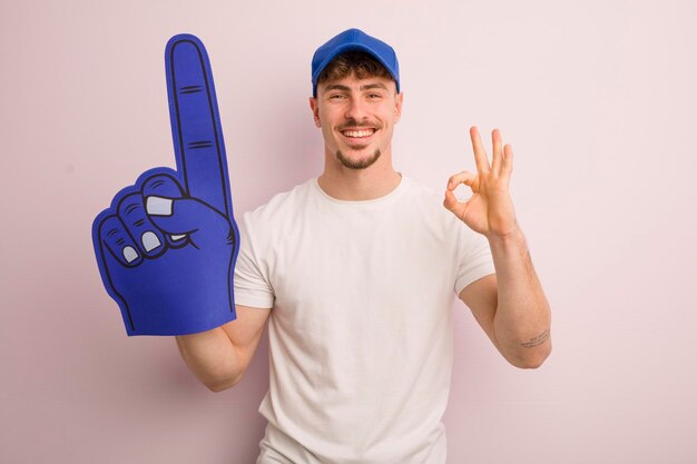 Young cool man feeling happy showing approval with okay gesture number one fan concept