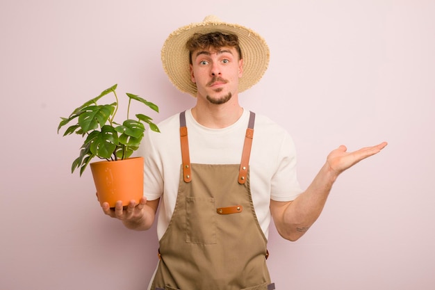 Young cool man feeling puzzled and confused and doubting gardener and plant