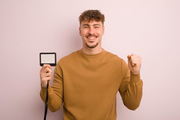 Young cool man feeling shockedlaughing and celebrating success vip pass id concept