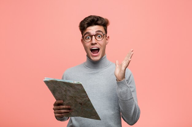 Young cool man holding a map happy, smiling and cheerful.