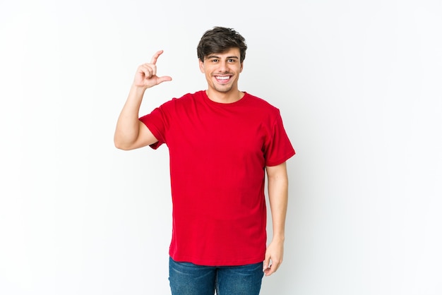 Photo young cool man holding something little with forefingers, smiling and confident.