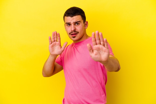 Young cool man isolated on yellow wall being shocked due to an imminent danger