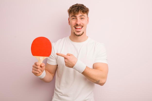 Young cool man looking excited and surprised pointing to the side pingpong concept