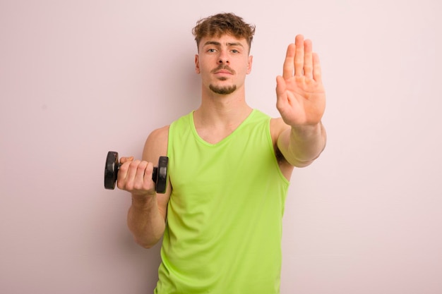 Photo young cool man looking serious showing open palm making stop gesture fitness concept