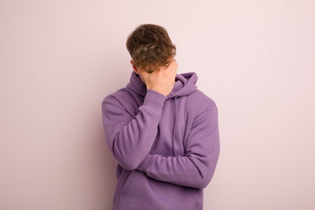 Young cool man looking stressed ashamed or upset with a headache covering face with hand