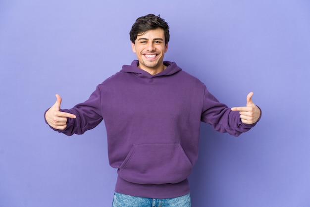 Young cool man points down with fingers, positive feeling.