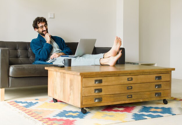 Young cool man sitting on a sofa at living room watching tv