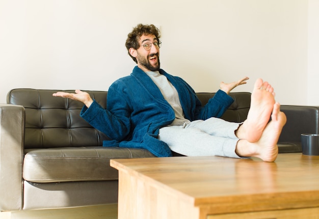 Young cool man sitting on a sofa at living room watching tv