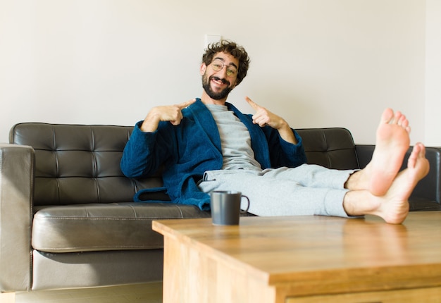 Young cool man sitting on a sofa at living room watching tv