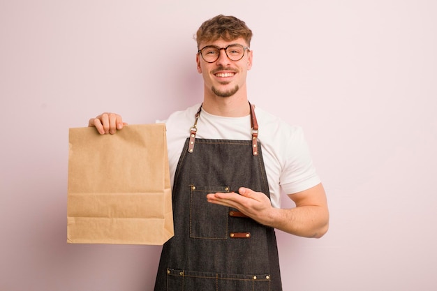 Young cool man smiling cheerfully feeling happy and showing a concept deliveryman and fast food