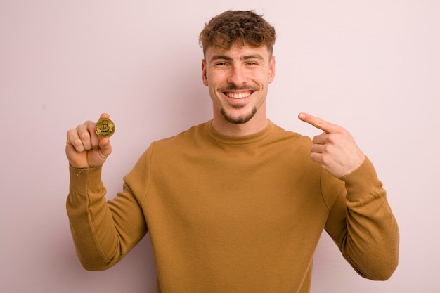 Young cool man smiling confidently pointing to own broad smile bitcoin concept