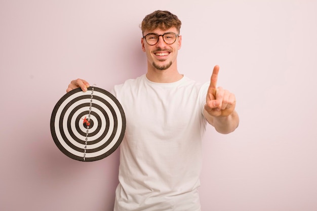 Young cool man smiling and looking friendly showing number one dart target concept