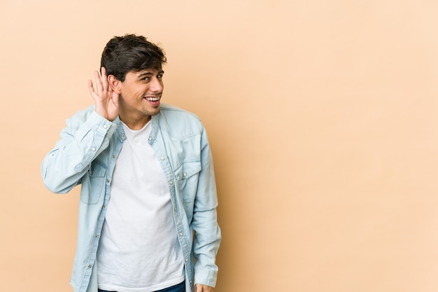 Young cool man trying to listening a gossip.