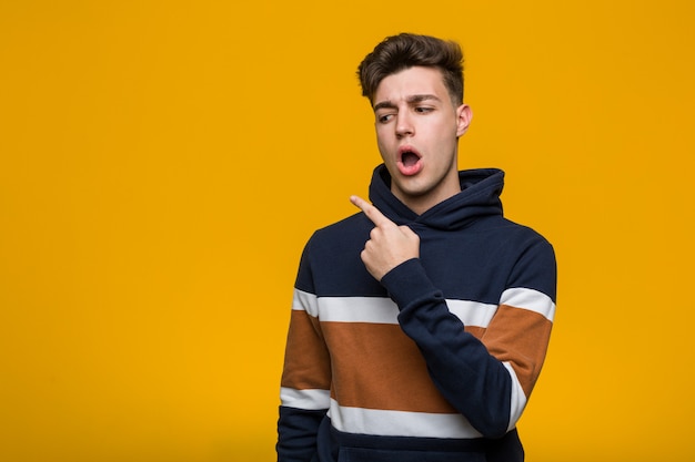 Young cool man wearing a hoodie pointing to the side