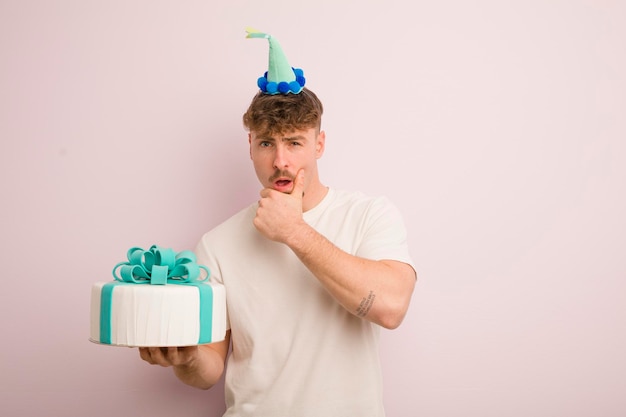 Young cool man with mouth and eyes wide open and hand on chin birthday concept