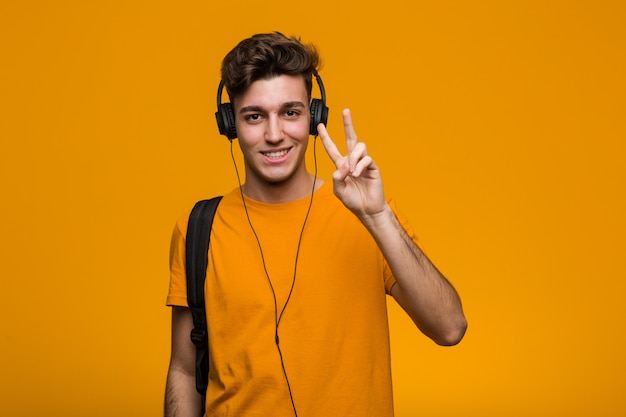 Young cool student man listening to music with headphones having some great idea