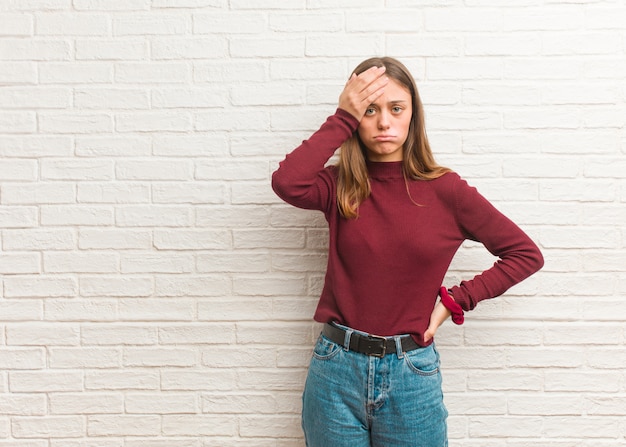 Young cool woman over a bricks wall tired and very sleepy