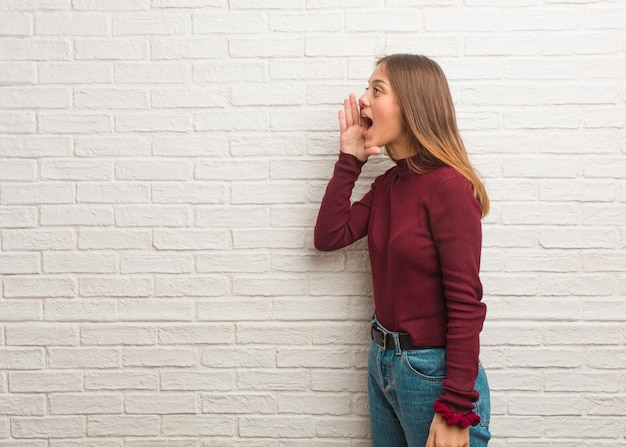 Young cool woman over a bricks wall whispering gossip undertone