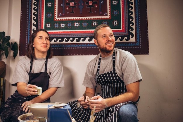 Young couple in apron at artwork in pottery
