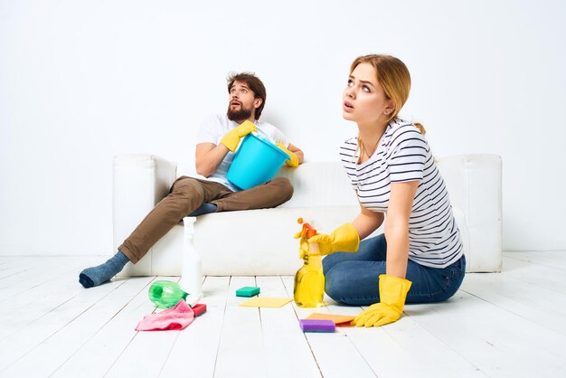 Photo young couple are doing cleaning together in the room light background high quality photo