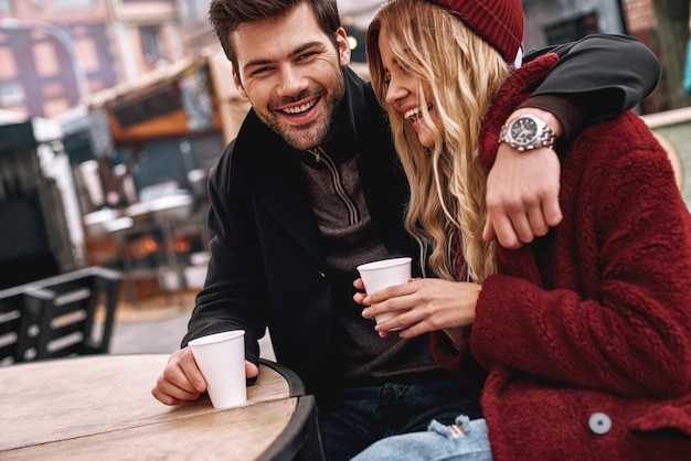 写真 若いカップルが熱い飲み物のお茶やコーヒーを飲みながら話している