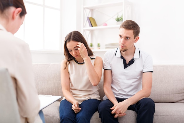 Young couple arguing on couch during therapy session. Relationship problems, family issues concept