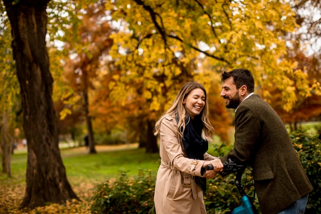 Young couple in the autumn park with electrical bicycle