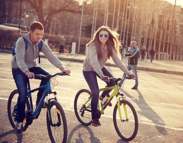 Giovani coppie sulle biciclette nella città al tramonto