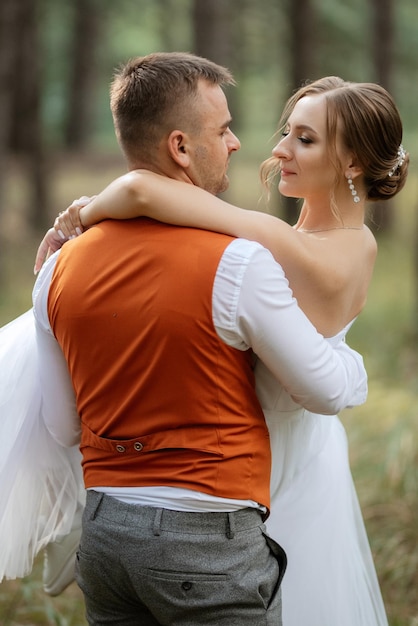 Young couple bride in a white short dress and groom in a gray suit in a pine forest