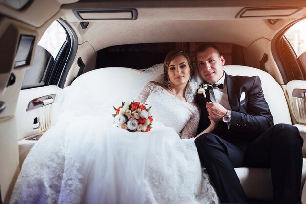 Young couple in a car in wedding day