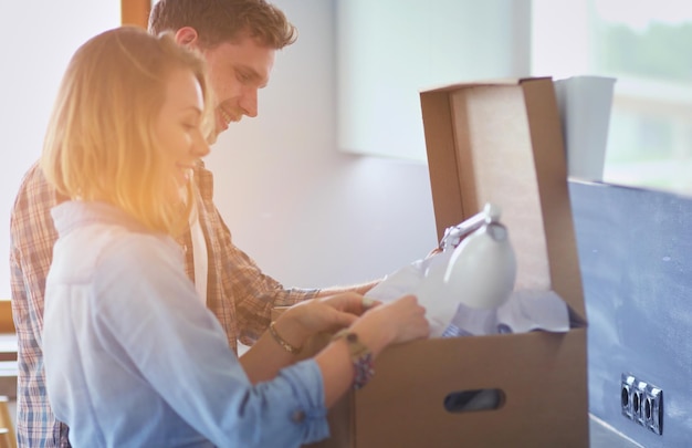 Young couple carrying big cardboard box at new homeMoving house Young couple