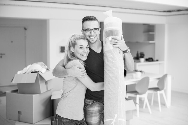 Photo young couple carrying a carpet moving in to new home together. home, people, moving and real estate concept