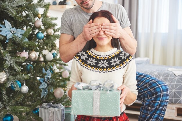 若いカップルがクリスマスを祝います。男が突然妻にプレゼントを贈りました。家族の幸せと幸福の概念