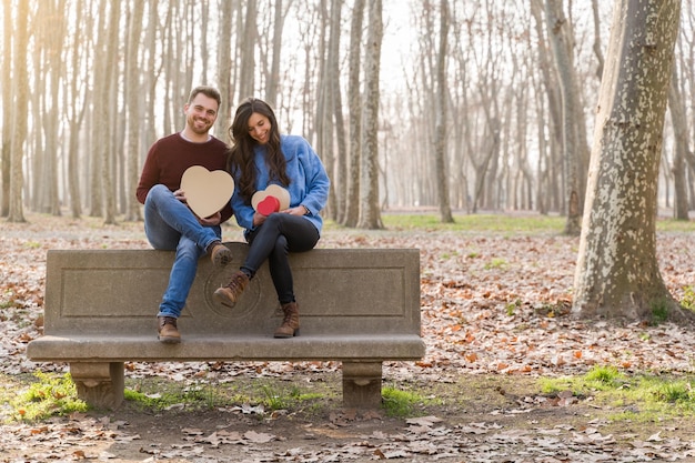 Young couple celebrating valentine39s day giving each other a gift sitting on a park bench