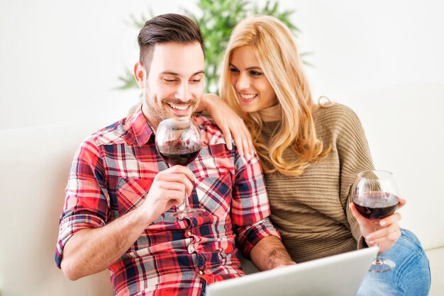 Молодая пара празднует дома с красным вином
