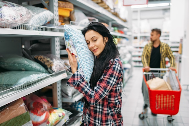 Young couple choosing pillow in supermarket