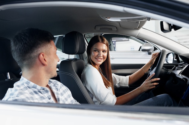 Young couple choosing their new car in a car shop together