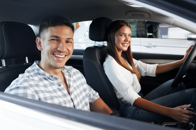 Young couple choosing their new car in a car shop together