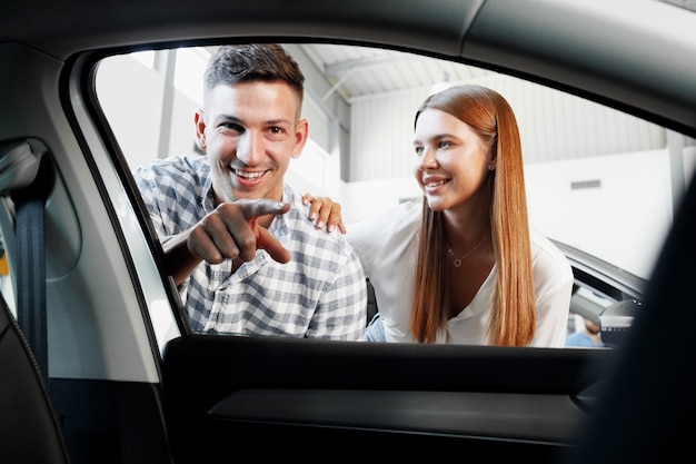 Young couple choosing their new car in a car shop